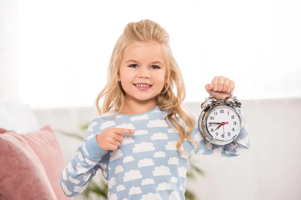 Smiling cute child pointing with finger at clock — Stock Photo