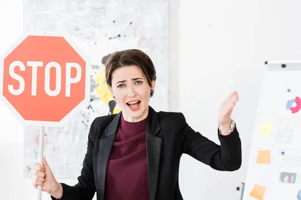Angry businesswoman holding stop sign and screaming in office — Stock Photo