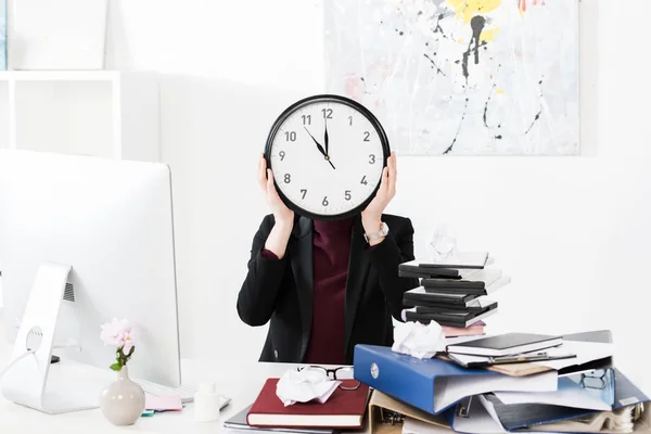 Femme d'affaires couvrant visage avec horloge dans le bureau — Photo de stock