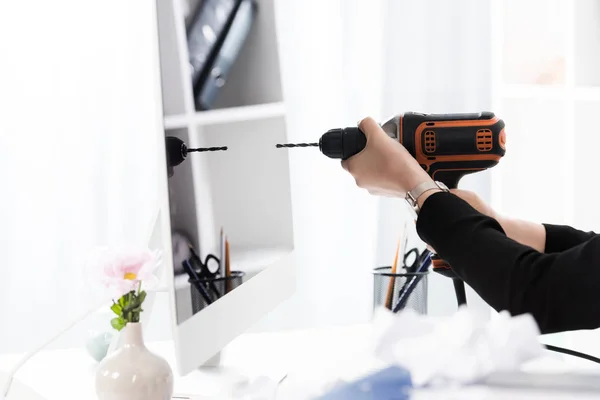 Imagen recortada de la mujer de negocios que va a perforar la computadora con taladro eléctrico en la oficina - foto de stock