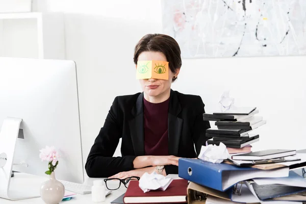 Mujer de negocios sentada con pegatinas en los ojos en la oficina - foto de stock