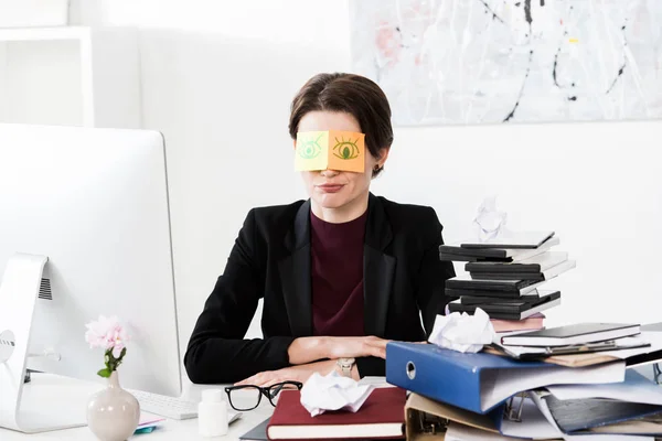 Femme d'affaires assis avec des autocollants sur les yeux dans le bureau — Photo de stock