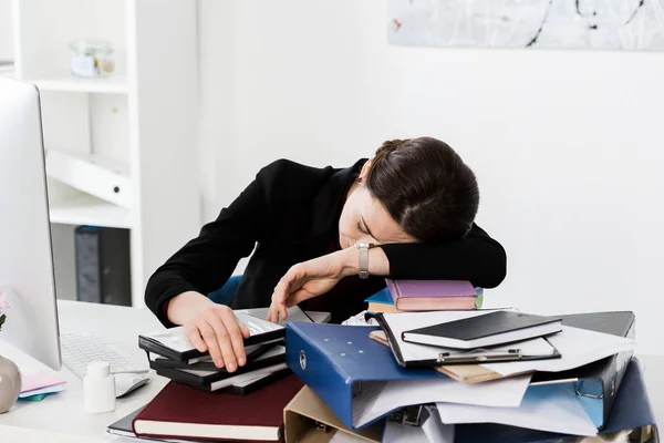 Femme d'affaires épuisée dormant sur des dossiers avec des documents à table au bureau — Photo de stock