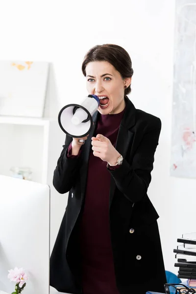 Agresiva mujer de negocios gritando en megáfono en la oficina - foto de stock