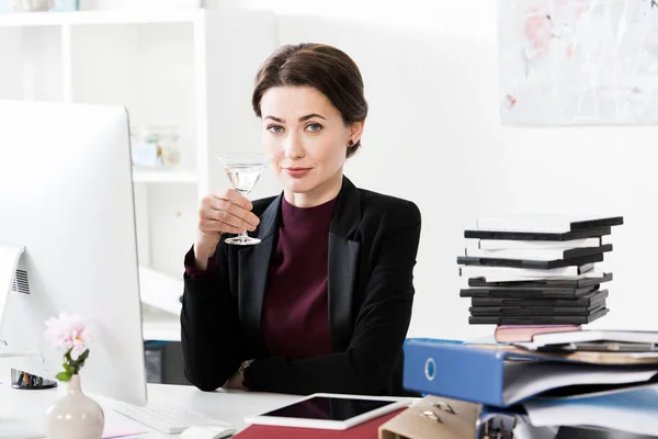Beautiful businesswoman holding cocktail in office — Stock Photo