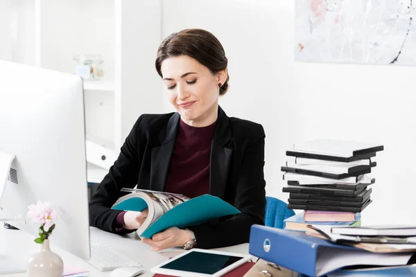 Atractiva mujer de negocios mirando libro abierto en la oficina - foto de stock