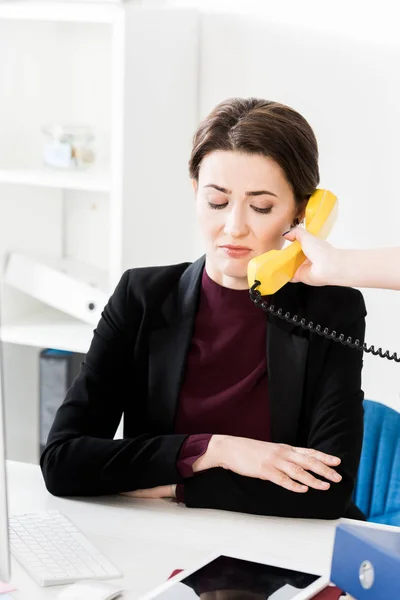 Femme d'affaires grimaçante parlant par téléphone fixe jaune dans le bureau — Photo de stock