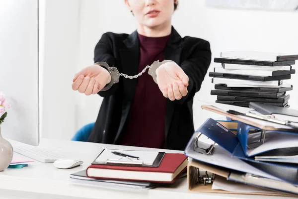 Immagine ritagliata di donna d'affari che mostra le mani con le manette in ufficio — Foto stock