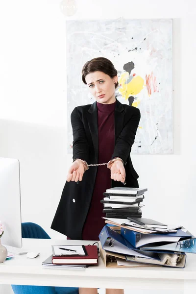 Traurige Geschäftsfrau zeigt Hände mit Handschellen im Büro — Stockfoto