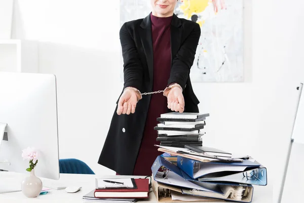 Cropped image of businesswoman showing hands with handcuffs in office — Stock Photo