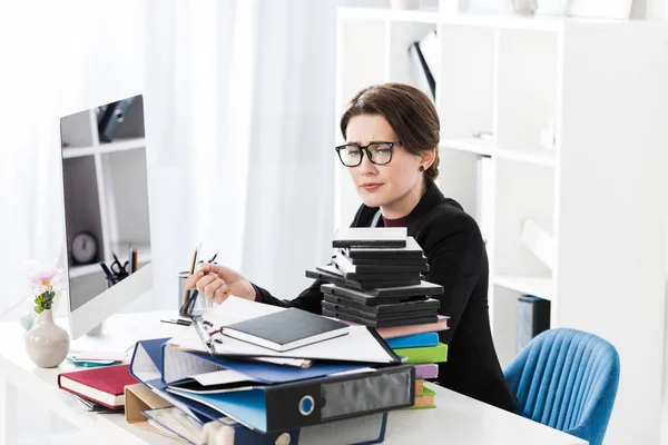Traurig müde attraktive Geschäftsfrau mit Brille schaut auf Stapel von Dokumenten im Büro — Stockfoto