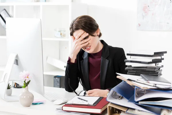 Sad exhausted businesswoman touching forehead at table in office — Stock Photo