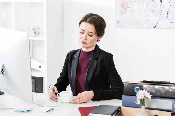 Attraente donna d'affari che tiene una tazza di tè a tavola in ufficio — Foto stock