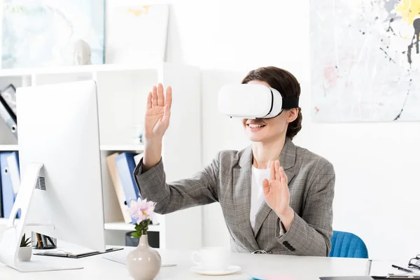 Улыбающаяся деловая женщина, использующая гарнитуру виртуальной реальности в офисе — стоковое фото