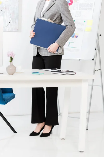 Section basse de la femme d'affaires tenant dossier avec des documents dans le bureau — Stock Photo