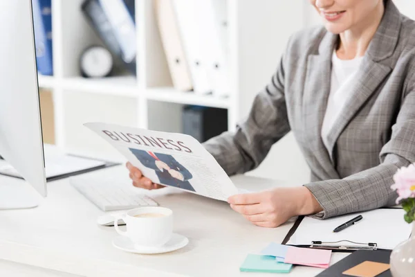 Cropped image of businesswoman reading newspaper in office — Stock Photo