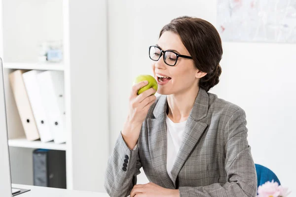 Attraktive Geschäftsfrau isst Apfel im Büro — Stockfoto