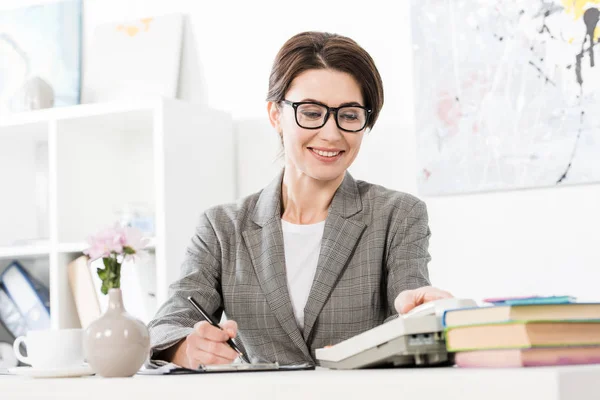 Surface level of smiling attractive businesswoman answering stationary telephone in office — Stock Photo