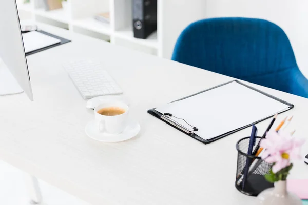 High angle view of cup of coffee and clipboard on table in business office — Stock Photo