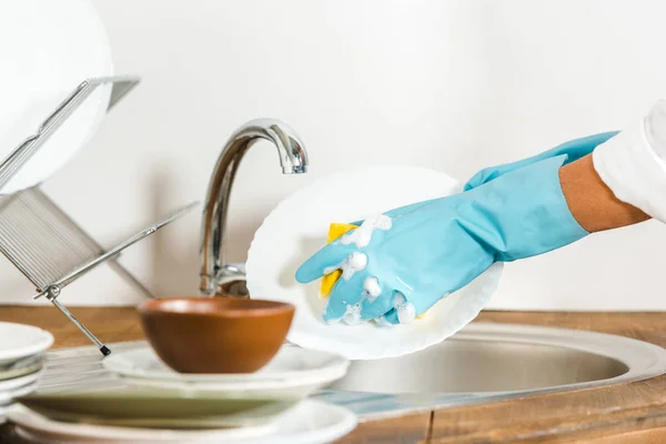 Imagen recortada de la mujer madura lavando platos en la cocina - foto de stock