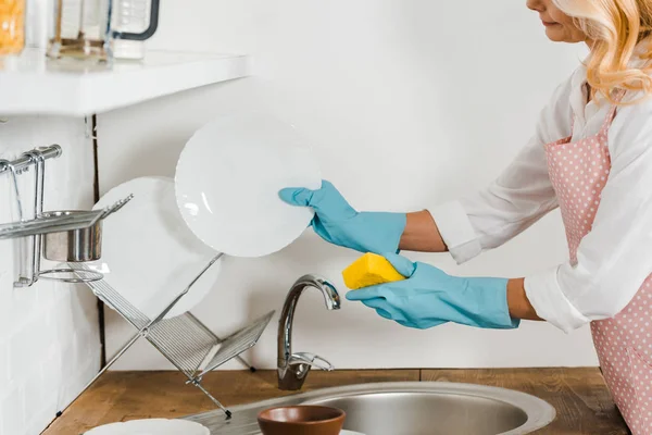 Imagen recortada de mujer de mediana edad lavando platos en la cocina - foto de stock