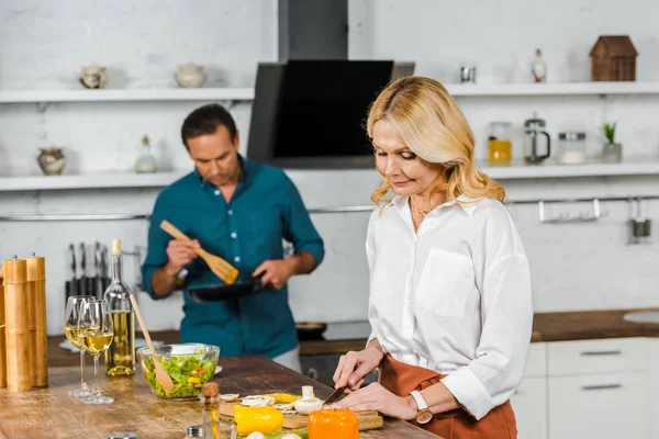 Mature wife and husband cooking together in kitchen — Stock Photo
