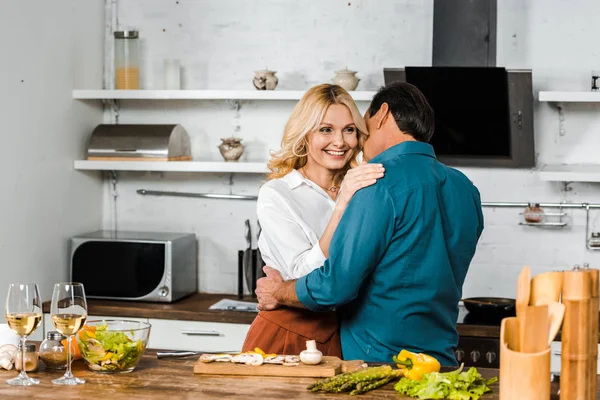 Happy mature wife and husband hugging in kitchen — Stock Photo