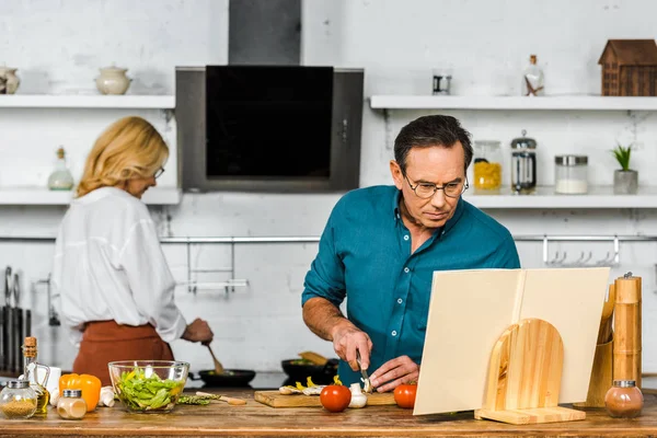 Mature couple cooking together in kitchen — Stock Photo