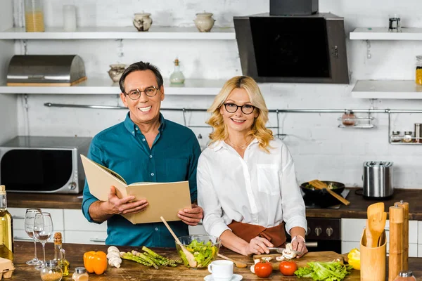Високий кут зору зрілої дружини і чоловіка, що готує разом з книгою рецептів на кухні — стокове фото