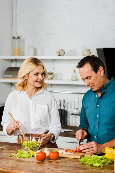 Зрелая жена и муж готовят здоровый салат вместе на кухне — стоковое фото