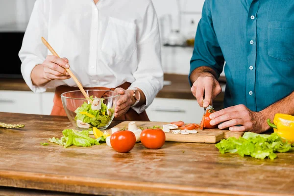 Cropped image of mature wife and husband cooking healthy salad together in kitchen — Stock Photo