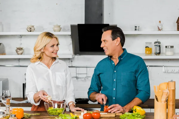 Mature couple cooking organic salad together in kitchen — Stock Photo