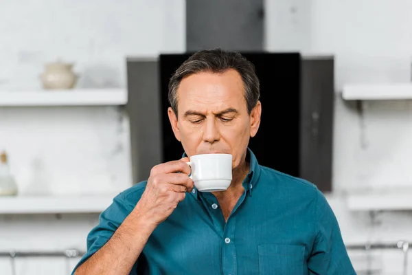 Красивый мужчина средних лет пьет чай на кухне — стоковое фото