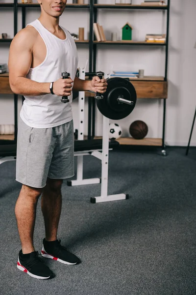 Ausgeschnittene Ansicht eines zweirassigen Mannes beim Training mit Hanteln im Wohnzimmer — Stockfoto