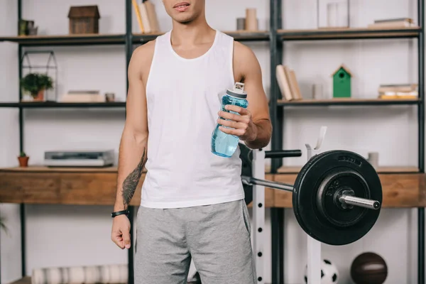 Vue recadrée de l'homme bi-racial debout avec bouteille de sport — Photo de stock