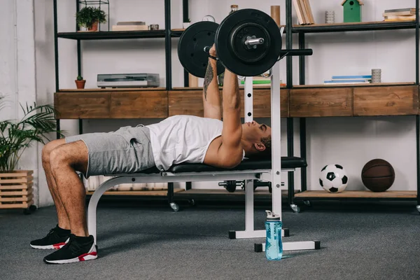 Musculosa carrera mixta hombre entrenamiento con barra de pesas en casa gimnasio - foto de stock