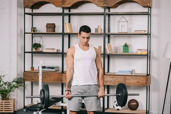 Красивый татуированный двурасовый мужчина, тренирующийся в домашнем спортзале — стоковое фото