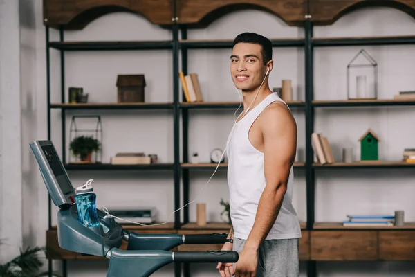 Cheerful bi-racial sportsman listining music in earphones — Stock Photo