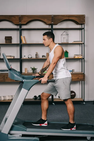 Muscular bi-racial sportsman walking on treadmill — Stock Photo