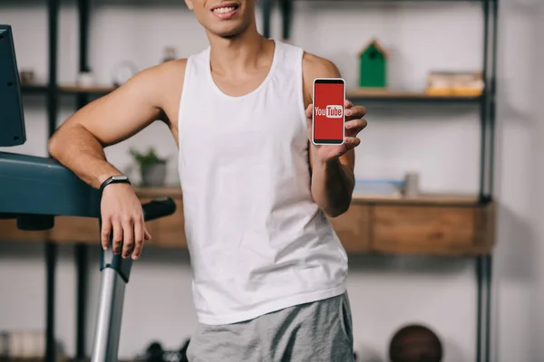 Vista cortada de homem de raça mista segurando smartphone com aplicativo youtube na tela — Fotografia de Stock