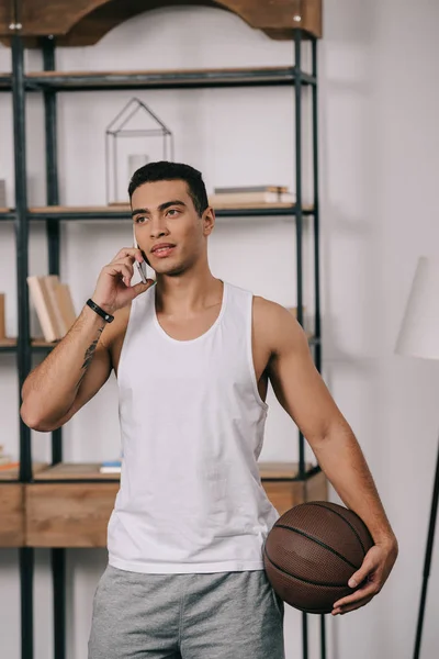 Schöner Mann mit zwei Rassen, der mit dem Smartphone spricht, während er Basketball spielt — Stockfoto