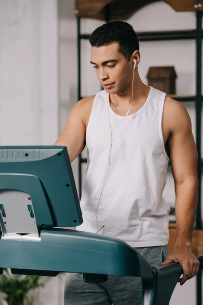 Mixed race man listening music in earphones while exercising on treadmill — Stock Photo