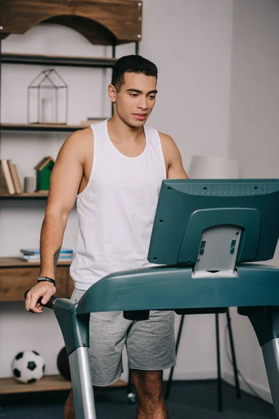 Fuerte musculoso bi-racial hombre ejercitando en cinta de correr en sala de estar - foto de stock