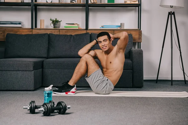 Bel homme bi-racial exerçant sur tapis de fitness dans la salle de gym à domicile — Photo de stock