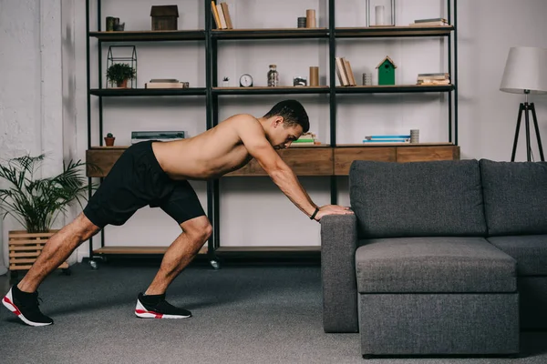 Handsome mixed race man doing exercise in living room — Stock Photo