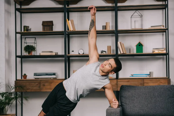Handsome bi-racial man doing plank exercise in sportswear in living room — Stock Photo