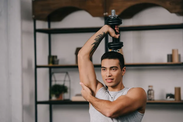 Hombre bi-racial muscular con entrenamiento de tatuaje en la sala de estar - foto de stock