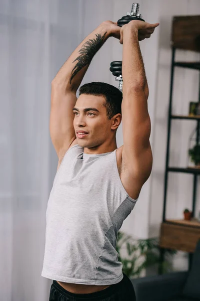 Muscular bi-racial man with tattoo workout with dumbbell — Stock Photo