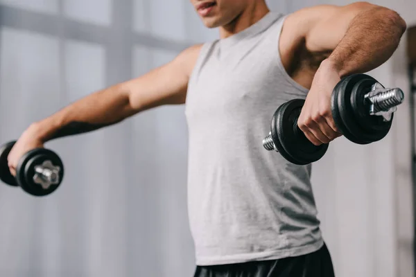 Vista ritagliata bi-razziale uomo allenamento con manubri — Stock Photo