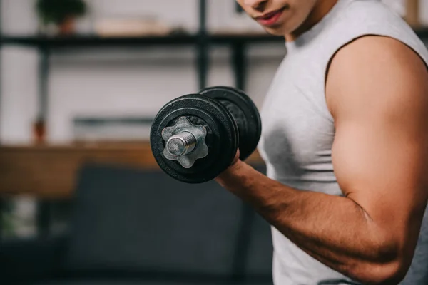 Cropped view of mixed race sportsman training with heavy dumbbell — Stock Photo